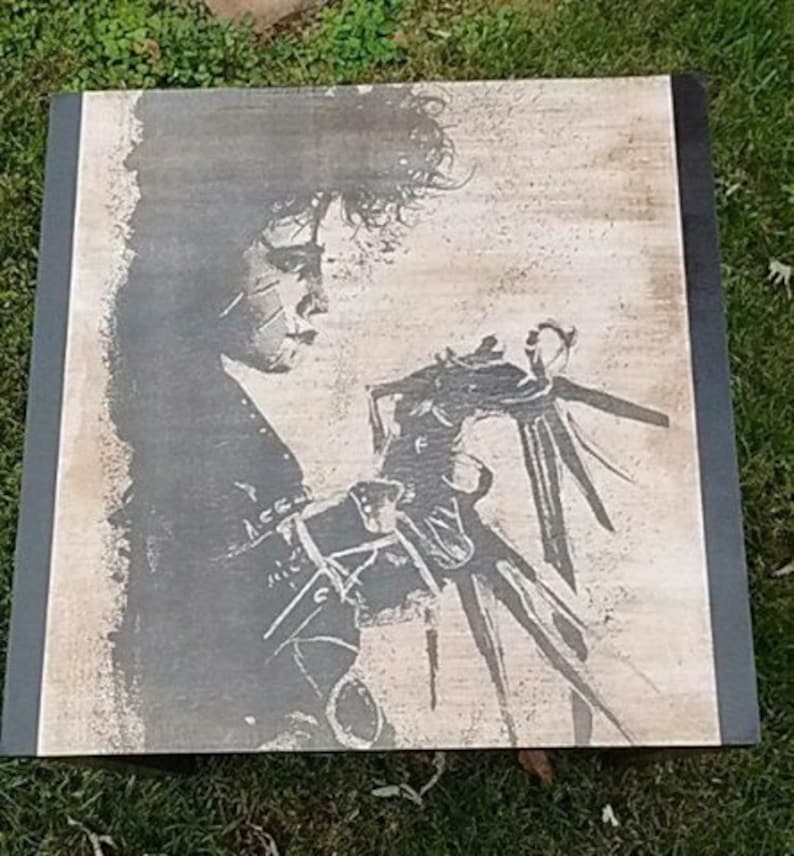 May include: A black and white wood print of a character from the film Beetlejuice. The character is holding a pair of large, sharp scissors.