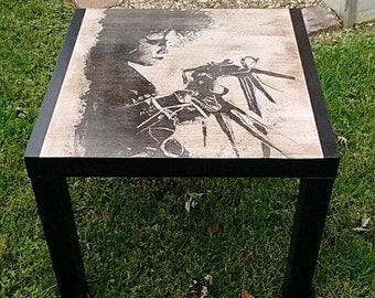 Puede incluir: Mesa de café negra con una tapa cuadrada que presenta una imagen en blanco y negro de una persona con una mano grande. La mesa tiene un marco negro.