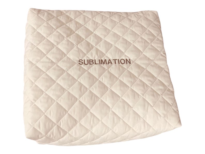 May include: A square, off-white quilted fabric cover featuring a diamond-stitched pattern across its surface. The word SUBLIMATION is embroidered in a dark brown thread in the center of the fabric, providing a clear contrast against the light background.