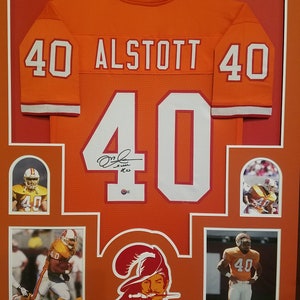 May include: A framed orange football jersey with the name "ALSTOTT" and the number "40" on the back. The jersey is signed by the player. There are four smaller photos of the player in the frame.