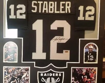 May include: Framed black Raiders jersey with the name "STABLER" and the number "12" in white. Includes photos of the player in action and the Raiders logo. A great gift for any football fan.