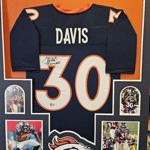 May include: A framed Denver Broncos jersey with the number 30 and the name "DAVIS" on the back. The jersey is signed by the player. The frame includes photos of the player in action.