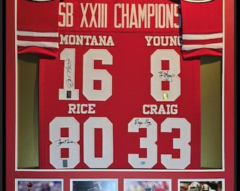 Könnte beinhalten: Ein gerahmtes rotes Trikot mit dem Logo der San Francisco 49ers und dem Text "SB XXIII CHAMPIONS". Das Trikot trägt die Nummern 16, 80 und 33 mit den Namen MONTANA, RICE und CRAIG darunter. Das Trikot ist von Joe Montana, Jerry Rice und Roger Craig signiert.