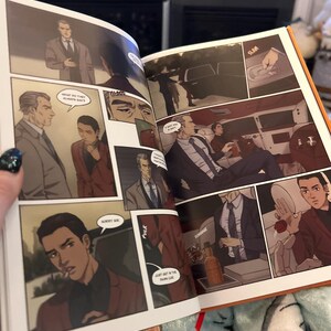 K&ouml;nnte beinhalten: Offenes Buch mit Comic-Illustrationen. Das Buch ist auf einer Seite ge&ouml;ffnet, die eine Szene zeigt, in der ein Mann im Anzug in ein Auto steigt. Der Text im Bild lautet "What the three always say" und "Don't get in the trunk car".