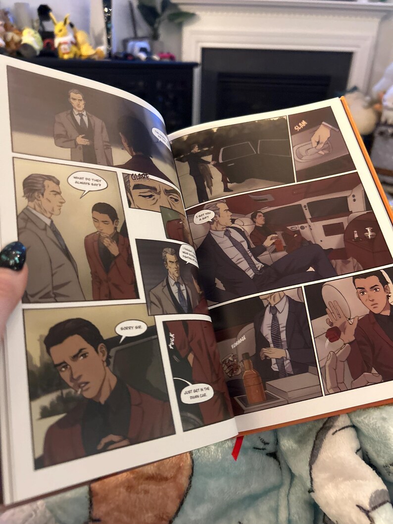 K&ouml;nnte beinhalten: Offenes Buch mit Comic-Illustrationen. Das Buch ist auf einer Seite ge&ouml;ffnet, die eine Szene zeigt, in der ein Mann im Anzug in ein Auto steigt. Der Text im Bild lautet "What the three always say" und "Don't get in the trunk car".