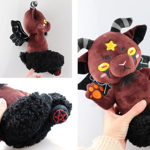 Puede incluir: Un juguete de peluche con forma de diablo marr&oacute;n con alas, cuernos y cola negros. El juguete tiene una estrella amarilla en la frente y huellas de patas naranjas en las manos. El juguete est&aacute; sentado sobre un fondo blanco.