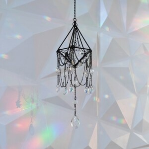 May include: A black metal geometric chandelier with crystal drops and crescent moon accents hanging from a white ceiling.