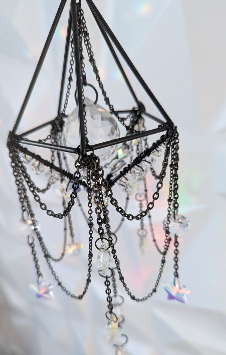 May include: A black metal geometric chandelier with crystal prisms and star-shaped accents hanging from chains.