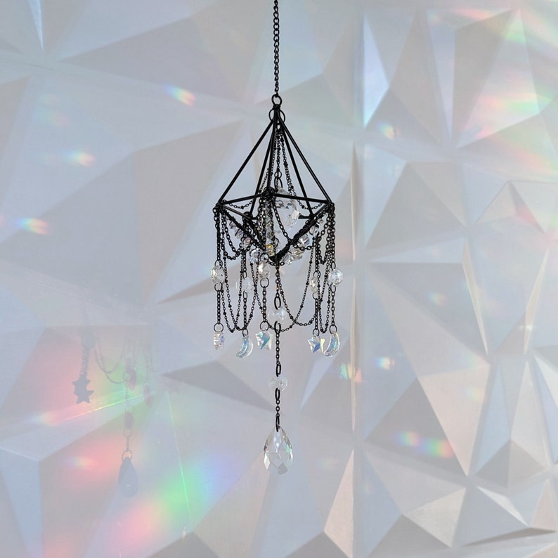 May include: A black metal geometric chandelier with crystal drops and crescent moon accents hanging from a white ceiling.