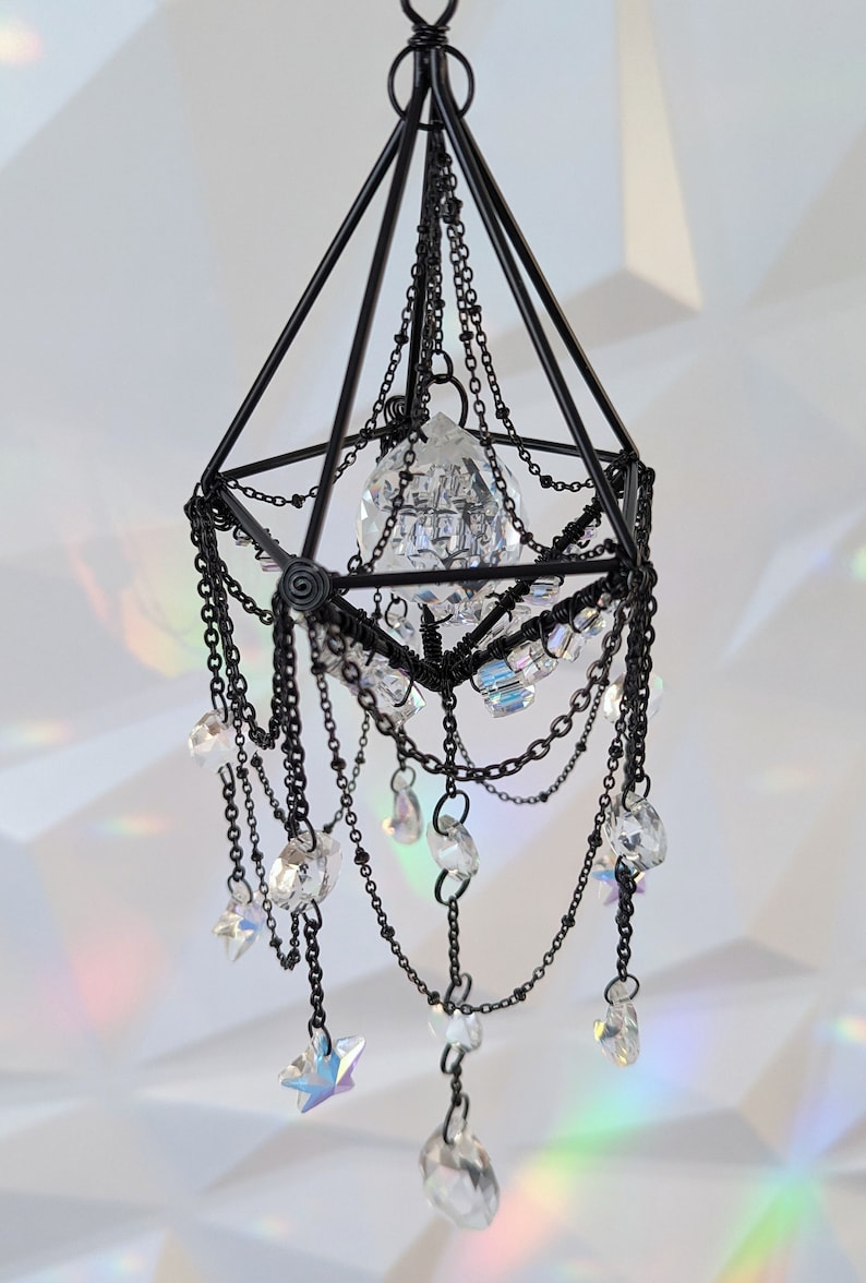 May include: A black metal geometric chandelier with crystal drops and a large crystal prism in the center.