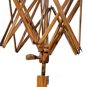 May include: A wooden yarn swift with a crank handle and a spindle. The swift is made of natural wood with a light brown finish. It is designed to hold yarn for winding.