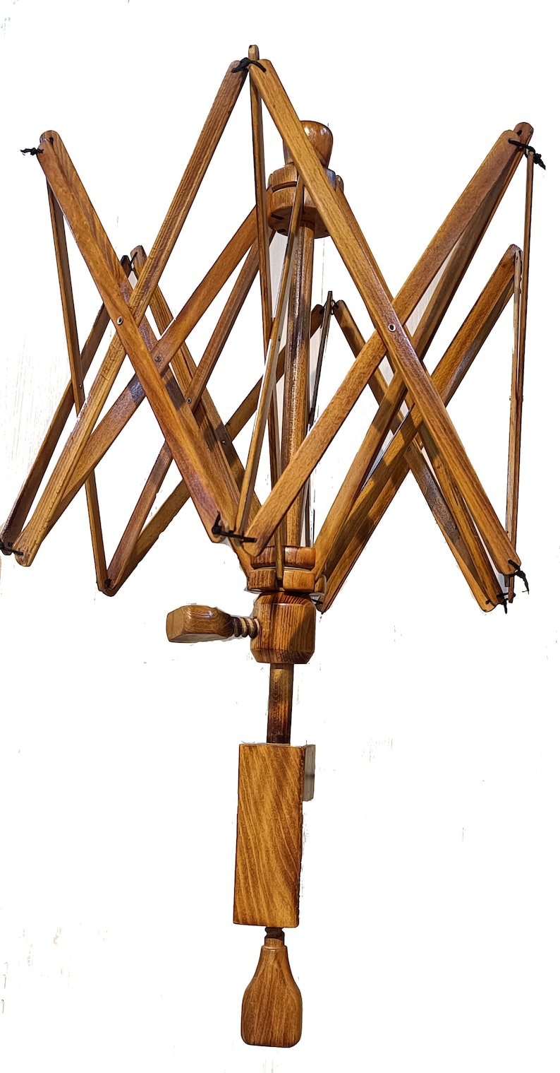 May include: A wooden yarn swift with a crank handle and a spindle. The swift is made of natural wood with a light brown finish. It is designed to hold yarn for winding.
