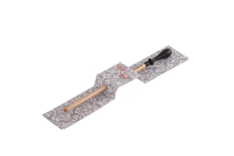 May include: A wooden knitting needle with a black plastic tip, packaged in a gray and white patterned paper wrapper. The wrapper has the text "Stitch & Story" printed on it.
