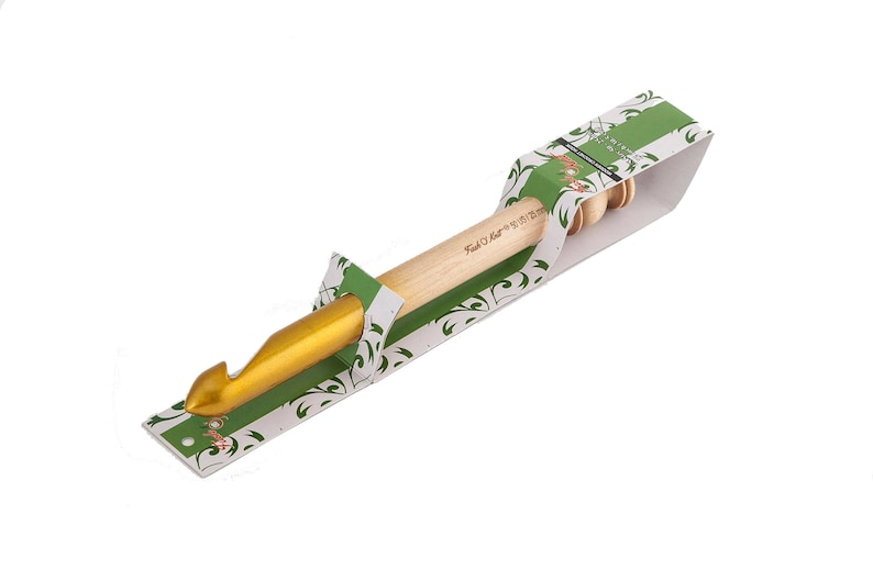May include: A gold crochet hook with a wooden handle, packaged in a green and white floral design box. The box has the text "Knit & Craft" printed on it.