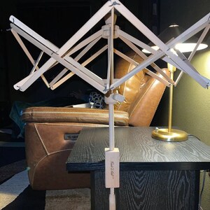 May include: A wooden yarn swift with a clamp that attaches to a table or chair. The swift is made of natural wood and has a simple design. The clamp is labeled "Fred O'Hair".