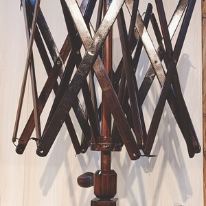 May include: A dark brown wooden yarn swift with a folding design. The swift has a crank handle and a base with the text "Furls O' Knit" engraved on it.