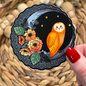 Pu&ograve; includere: Un adesivo con un'illustrazione stilizzata di un gufo arancione appollaiato su una luna crescente su sfondo nero. Il gufo &egrave; circondato da fiori arancioni e gialli e foglie verdi. La luna &egrave; decorata con un motivo mandala in bianco e nero.