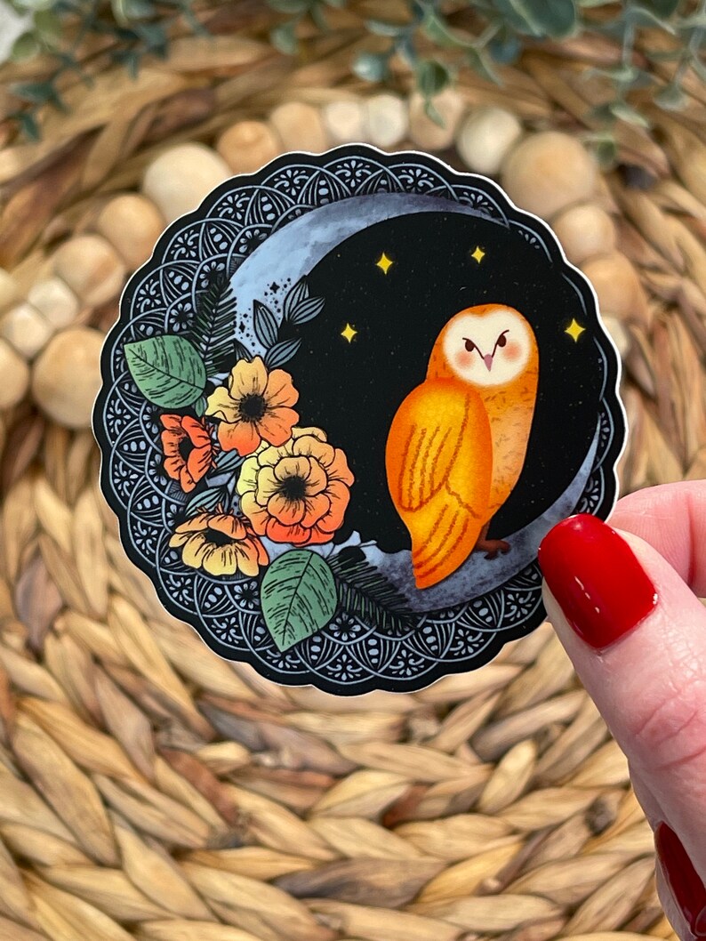 Pu&ograve; includere: Un adesivo con un gufo arancione appollaiato su una luna crescente su sfondo nero. Il gufo ha occhi gialli e una faccia bianca. La luna &egrave; circondata da un motivo floreale bianco e nero.