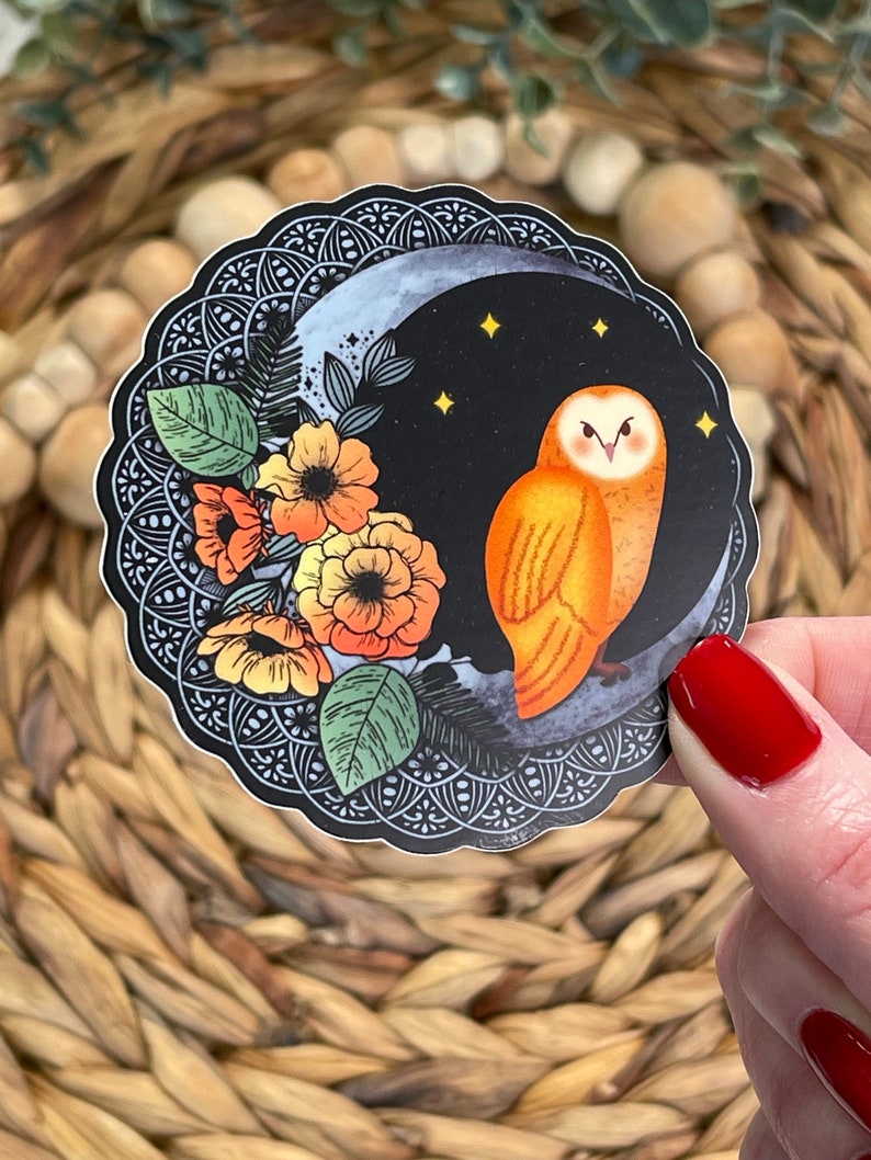 Pu&ograve; includere: Un adesivo con un gufo arancione appollaiato su una luna crescente su sfondo nero. Il gufo ha occhi gialli e un viso bianco. La luna &egrave; circondata da fiori arancioni e gialli e foglie verdi. L'adesivo ha un bordo intricato in bianco e nero.