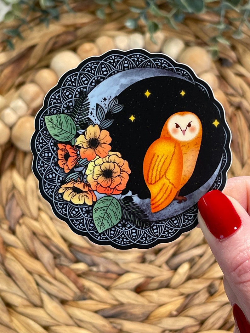 Pu&ograve; includere: Un adesivo con un gufo arancione appollaiato su una luna crescente con un design floreale. Il gufo ha occhi gialli e un becco nero. La luna &egrave; circondata da un design mandala in bianco e nero.