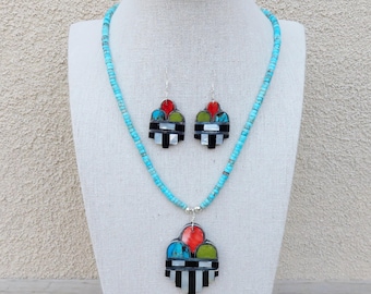 May include: A turquoise beaded necklace with a large pendant and matching earrings. The pendant and earrings are made of black, white, red, green, and blue stones.