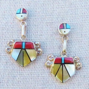 May include: A pair of dangle earrings with a geometric design. The earrings are made of silver and feature red, blue, white, and yellow stones.