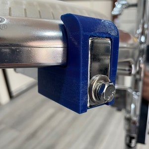 May include: A close-up of a blue plastic clamp attached to a silver metal object. The clamp has a metal screw and a metal plate.