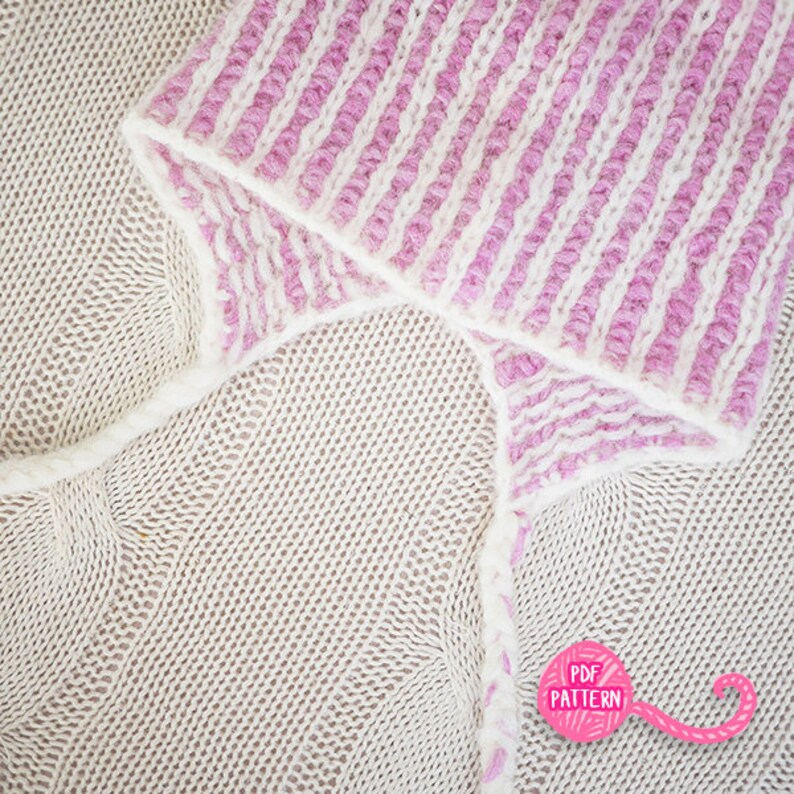 May include: Close-up of a knitted hat with a striped pattern in white and light purple. The hat is folded over a beige knitted fabric. The image includes a pink graphic with the text "PDF PATTERN".