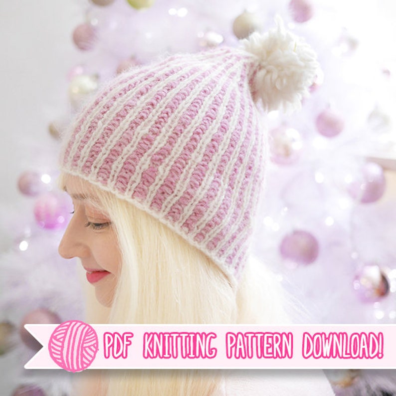 May include: A knitted hat with alternating pink and white stripes, topped with a white pom-pom. The hat is part of a PDF knitting pattern download, as indicated by the text in the image.