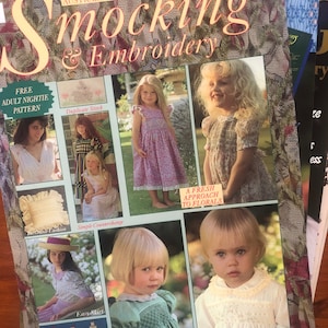 May include: A magazine cover for Australian Smocking & Embroidery, featuring a variety of smocking and embroidery projects, including a free adult nightie pattern, a duplicate stitch project, a simple counterchange project, an easy skirt project, a fresh approach to florals, and an embroidered baby dress. The magazine cover is a light brown color with a floral pattern.