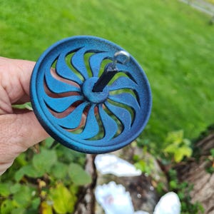 Könnte beinhalten: Ein blaues und grünes Spinnrad mit einer schwarzen Spindel und einem silbernen Haken. Das Rad hat ein Sternmuster.