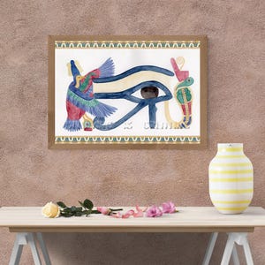 Puede incluir: Pintura a la acuarela enmarcada del Ojo de Horus, con un borde dorado y marrón. La obra de arte presenta el símbolo del ojo en tonos azules, amarillos y marrones, junto con otros símbolos egipcios. La pintura se exhibe en una pared marrón claro.