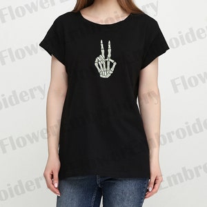 May include: Black t-shirt with a white skeleton hand making the peace sign.