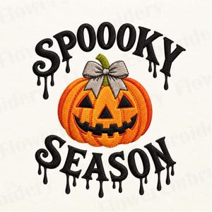 May include: An embroidered design featuring an orange jack-o'-lantern pumpkin with a grey bow on top. The text "SPOOOKY SEASON" is written in black, dripping-style lettering above and below the pumpkin, creating a festive Halloween graphic.