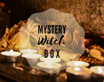 May include: A dimly lit scene featuring several lit tea light candles, dried leaves, and the text "MYSTERY Witch BOX". The background includes a blurred arrangement of white fabric and a stone surface, creating a mystical ambiance.
