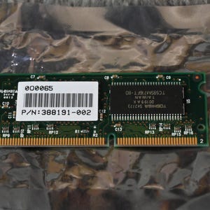 Könnte beinhalten: Eine grüne Leiterplatte mit goldenen Anschlüssen und schwarzen Chips. Ein weißes Etikett zeigt einen Barcode und den Text "P/N: 388191-002". Die Platine ist in einem silbernen, zerknitterten Kunststoff verpackt.