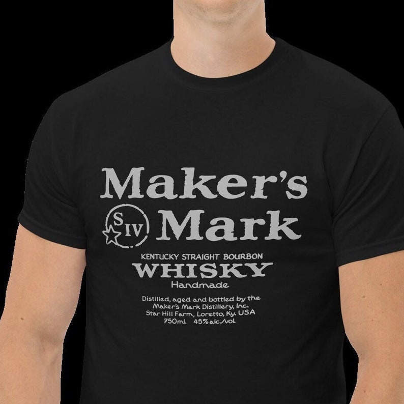 May include: Black t-shirt with a white graphic of the Maker's Mark whiskey label. The label features the brand name, a star with the Roman numeral IV, the words "Kentucky Straight Bourbon Whiskey", "Handmade", and the distillery information.