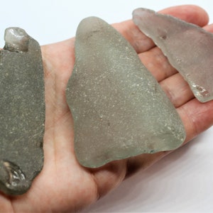 Puede incluir: Tres piezas de vidrio de mar, una es gris claro, otra es gris oscuro y la última es gris claro. El vidrio de mar es liso y ha sido pulido por el océano.