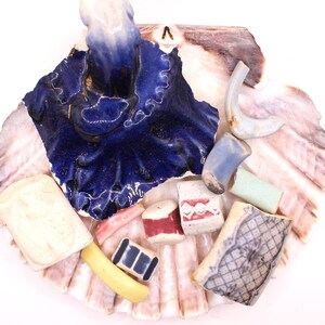 May include: A collection of colorful ceramic tiles arranged in a seashell. The tiles are various shapes and sizes, with some featuring patterns and others with solid colors. The tiles are arranged in a decorative manner, creating a unique and eye-catching display.