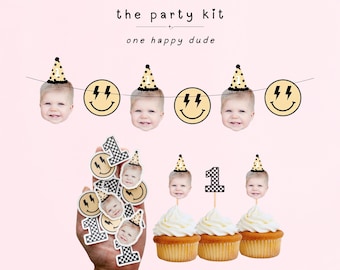 May include: A party kit featuring a banner with baby faces wearing party hats and lightning bolt smiley faces, plus cupcake toppers with baby faces and checkered number ones. The text reads the party kit and one happy dude.