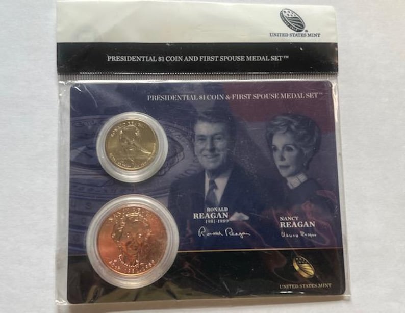 K&ouml;nnte beinhalten: Ein Set der United States Mint mit einer Presidential $1 M&uuml;nze und einer First Spouse Medaille. Das Set enth&auml;lt eine goldfarbene M&uuml;nze und eine kupferfarbene M&uuml;nze mit Portr&auml;ts von Ronald und Nancy Reagan. Die Verpackung tr&auml;gt den Text "PRESIDENTIAL $1 COIN AND FIRST SPOUSE MEDAL SET".