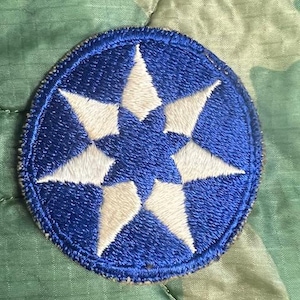 May include: A blue and white embroidered patch with a six-pointed star design. The patch is circular and has a white border.