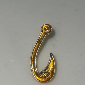 May include: A gold-colored fishing hook pin with a shiny finish.