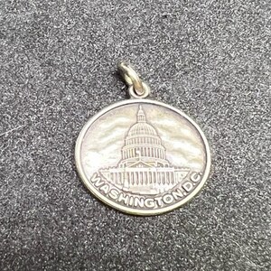 May include: Silver charm featuring a detailed image of the US Capitol building with the text "WASHINGTON, D.C." around the edge.