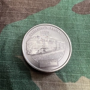 May include: Silver collector's series coin featuring a train with the text "EBM" and "FT DEMONSTRATOR 103".