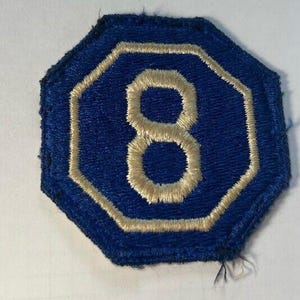 May include: A blue octagonal patch with a white number 8 embroidered on it.
