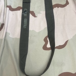 May include: A green military-style strap with a black button and a camouflage fabric patch. The strap is approximately 30 inches long.