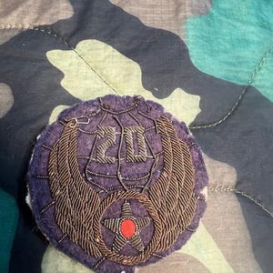 May include: A purple embroidered patch with a gold star and wings. The number "20" is embroidered in gold on the patch.