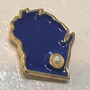 May include: A gold-toned pin in the shape of Wisconsin, filled with a deep blue enamel. A small, round, pearl-like accent is set near the bottom. The pin has a polished finish.