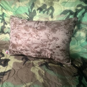 May include: A camouflage-patterned pillow with a soft, quilted texture. The pillow is made of a durable fabric and is perfect for adding a touch of military style to any room.